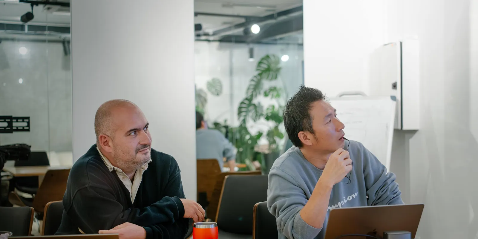 Two senior Applicable engineers at a meeting table, looking up at the work on screen